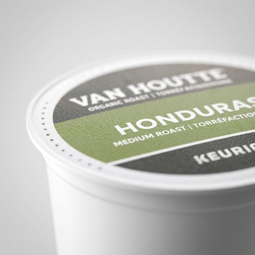 A macro photo of a Van Houtte Honduras K-Cup, showing the foil lid texture and printed text.
