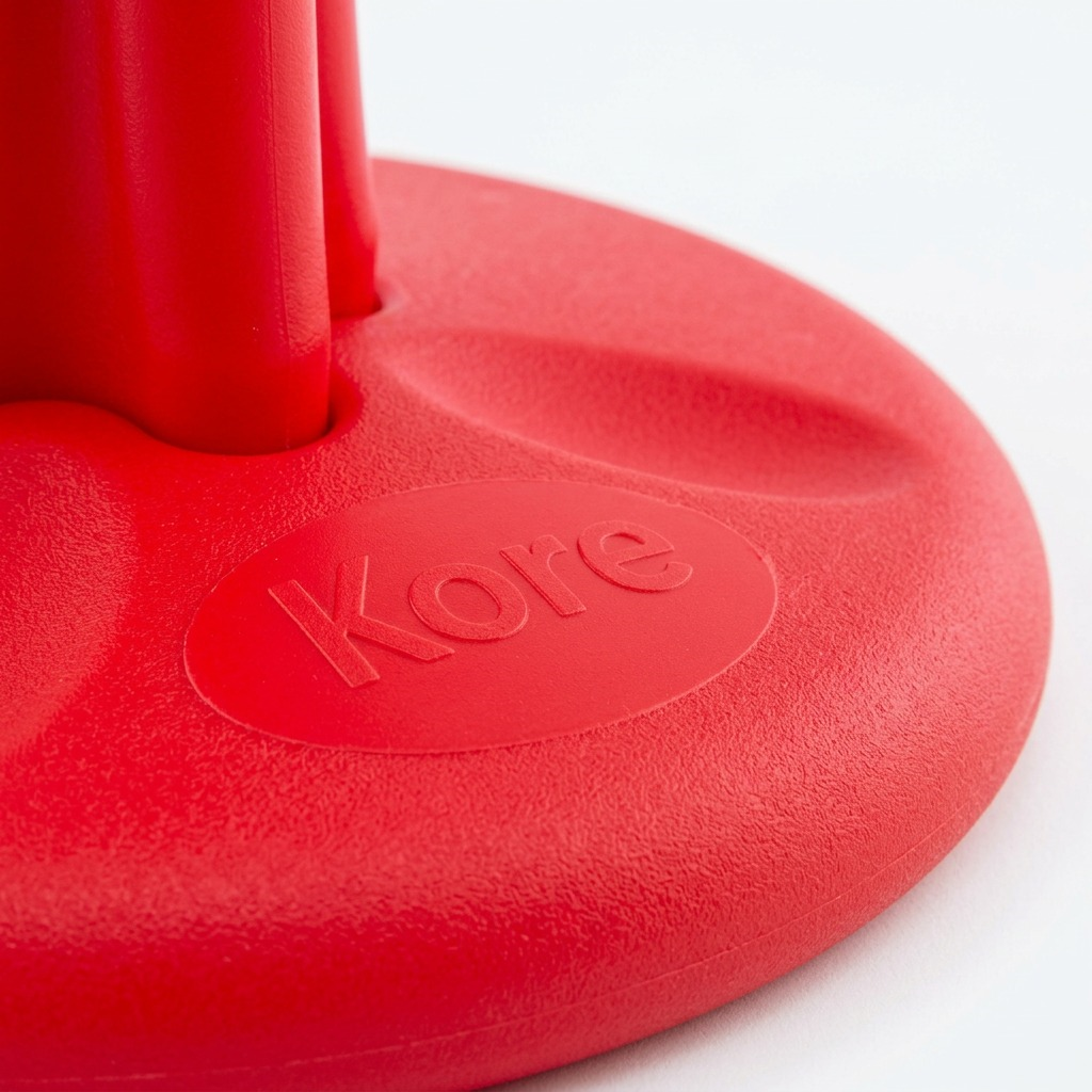 Macro detail of the embossed Kore logo on the textured red base of the 40cm Wobble Stool.